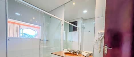 A modern bathroom with a glass shower enclosure, a vanity with a sink, and a large mirror.