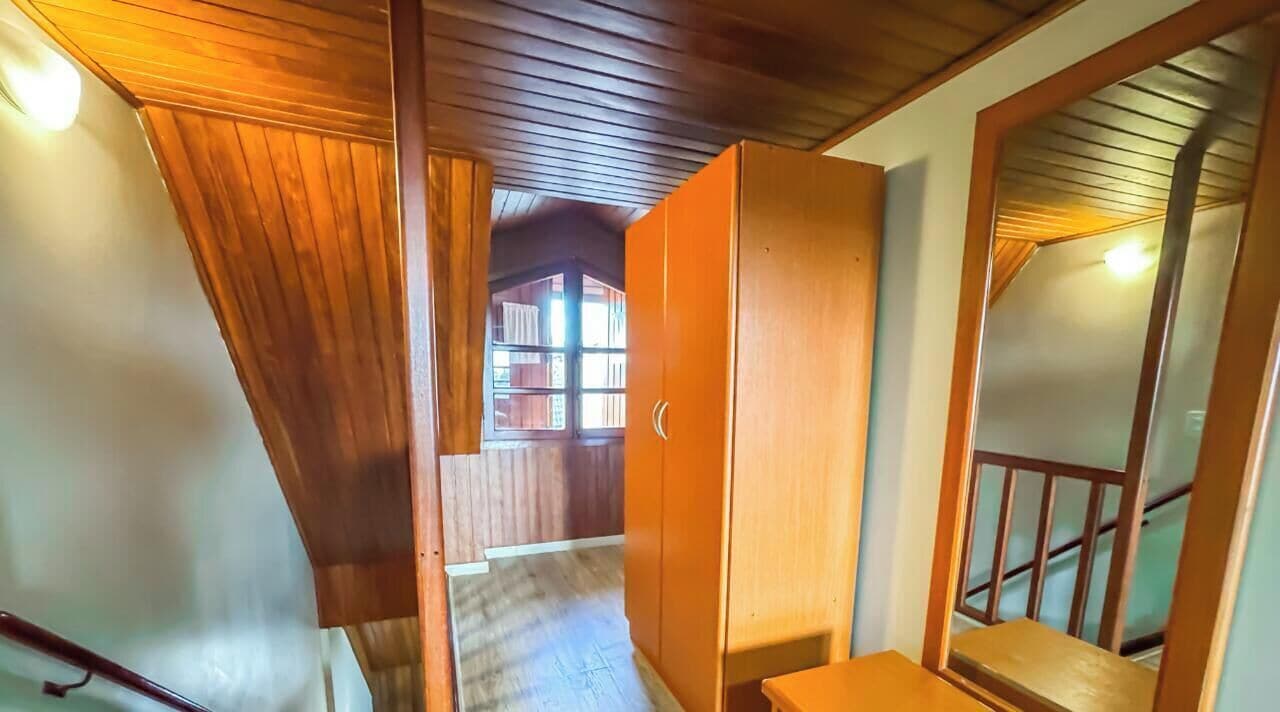 A wooden staircase leading to a loft bedroom with a large wardrobe and a view of the outside.