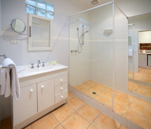 A modern bathroom with a glass-enclosed shower, a vanity with a mirror, and a sink. - Sorrento Beach Motel (Sorrento)