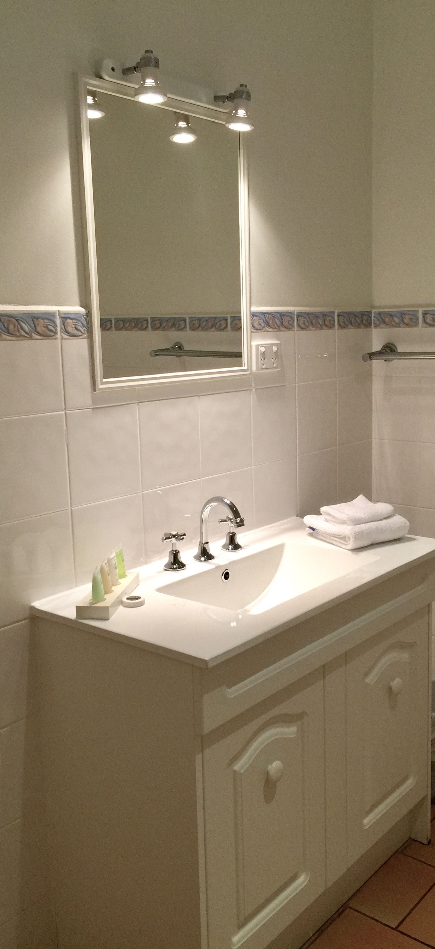 A bathroom with a white sink, a mirror, and a towel rack.