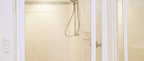 A shower enclosure with a tiled floor and a showerhead.