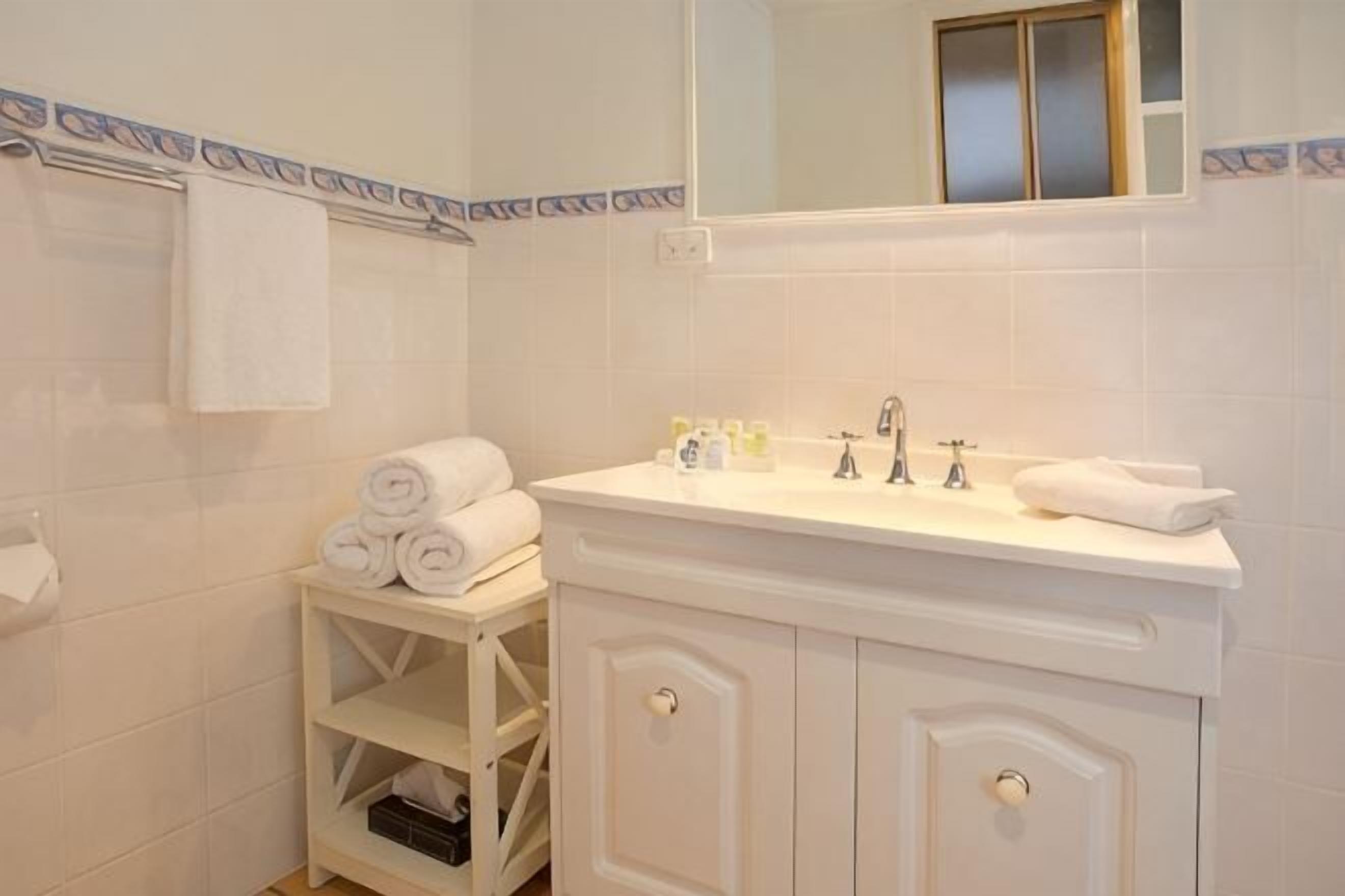 A bathroom with a white vanity, a mirror, and a towel rack.
