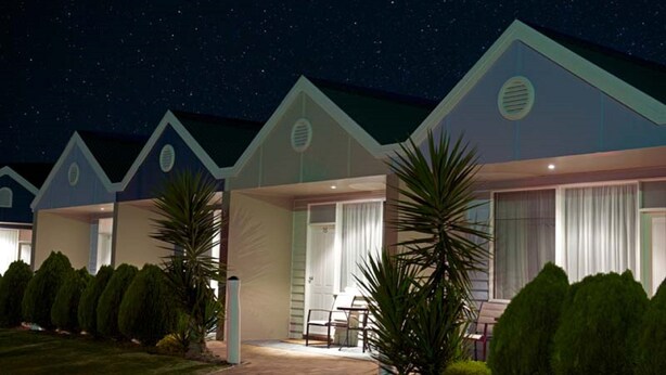 A row of modern, single-story cabins with a covered patio area, each with a door leading to a private room.