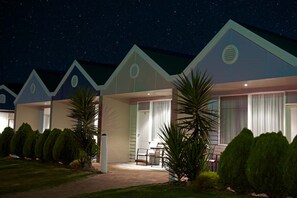 A row of modern, single-story cabins with a covered patio area, each with a door leading to a private room. - Sorrento Beach Motel (Sorrento)
