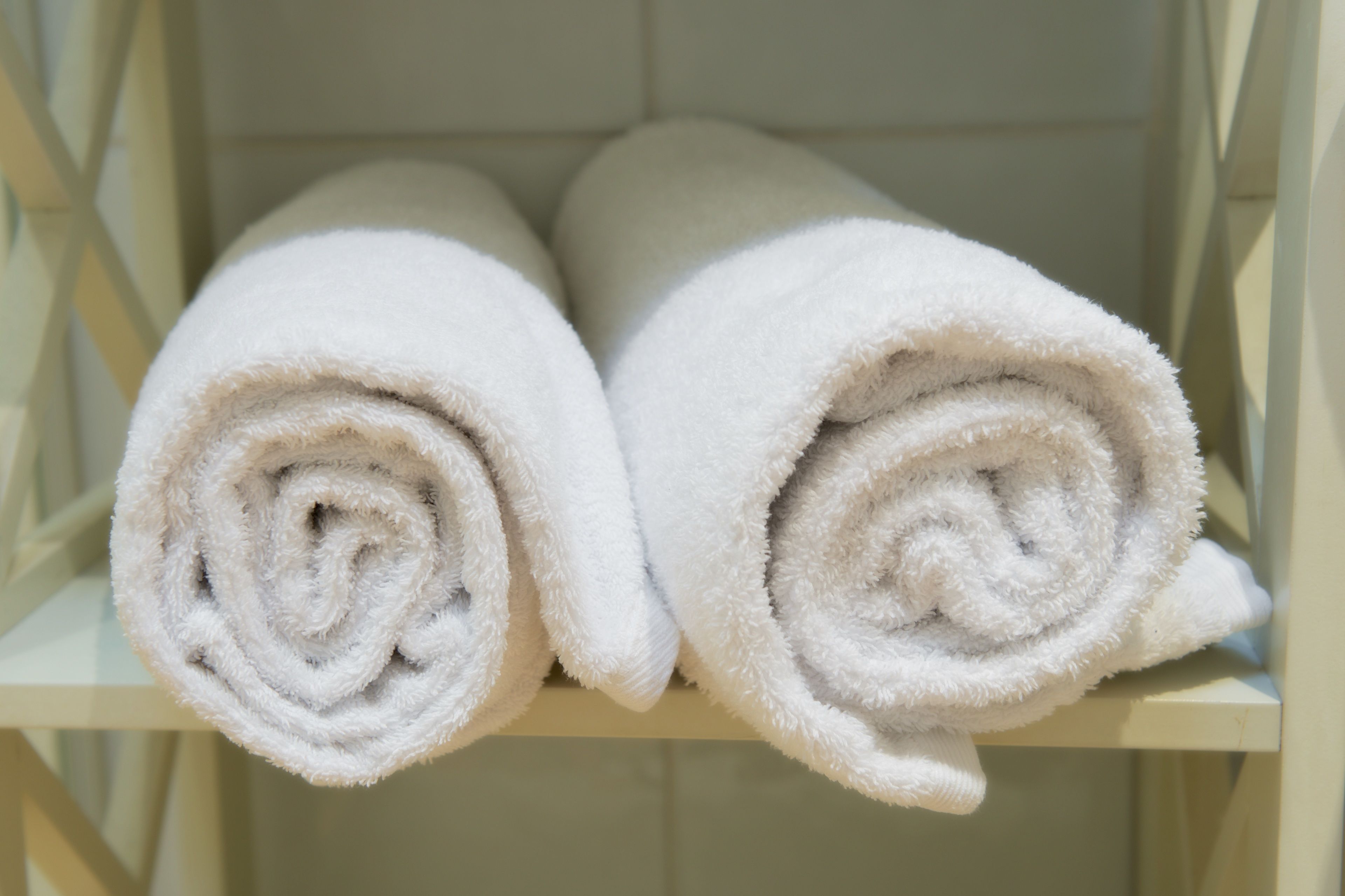 Two rolled white towels on a shelf.