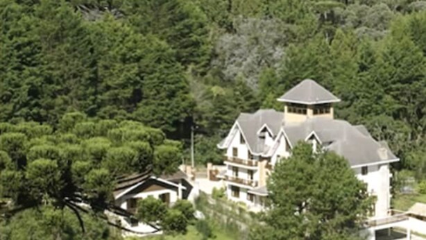 A large, multi-story house surrounded by dense forest. - Pousada Jóia da Serra (Campos do Jordão)