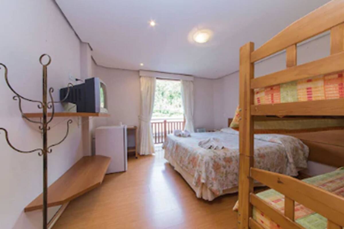 Una habitación con literas, un escritorio, una silla y una ventana con cortinas.