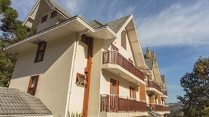 A multi-story building with a symmetrical facade, balconies, and a sloped roof. - Pousada Jóia da Serra (Campos do Jordão)