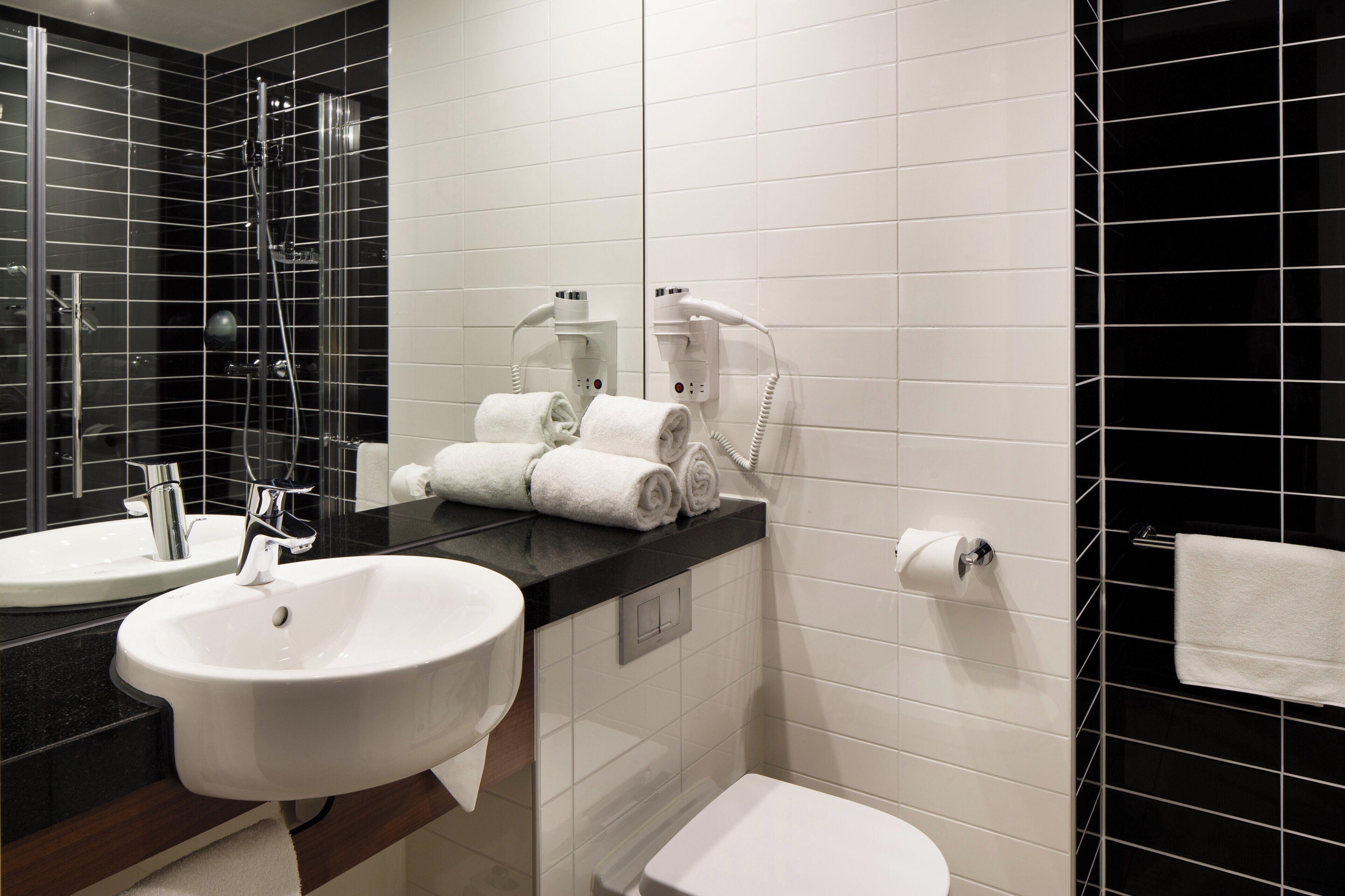 Un baño moderno con lavamanos, espejo y zona de ducha.
