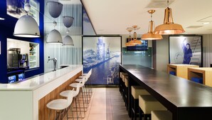 A modern bar area with a long counter, multiple seating options, and pendant lighting. - Holiday Inn Express Rotterdam - Central Station by IHG (Rotterdam)