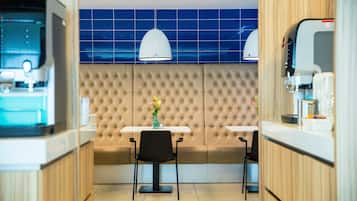 A modern kitchen with a central island, two bar stools, and a seating area with a tufted backrest.