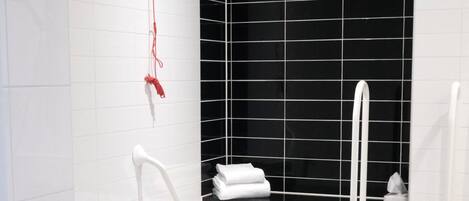 A modern bathroom with a white sink, toilet, and bidet. There is a black tiled wall and a white tiled floor.