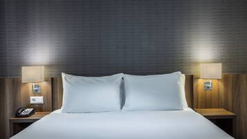 Habitación de hotel con una cama grande, dos mesitas de noche, un teléfono y lámparas de pared.