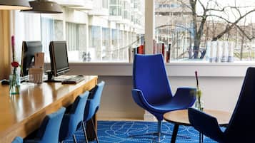 A modern office space with a desk, computer, and blue chairs.