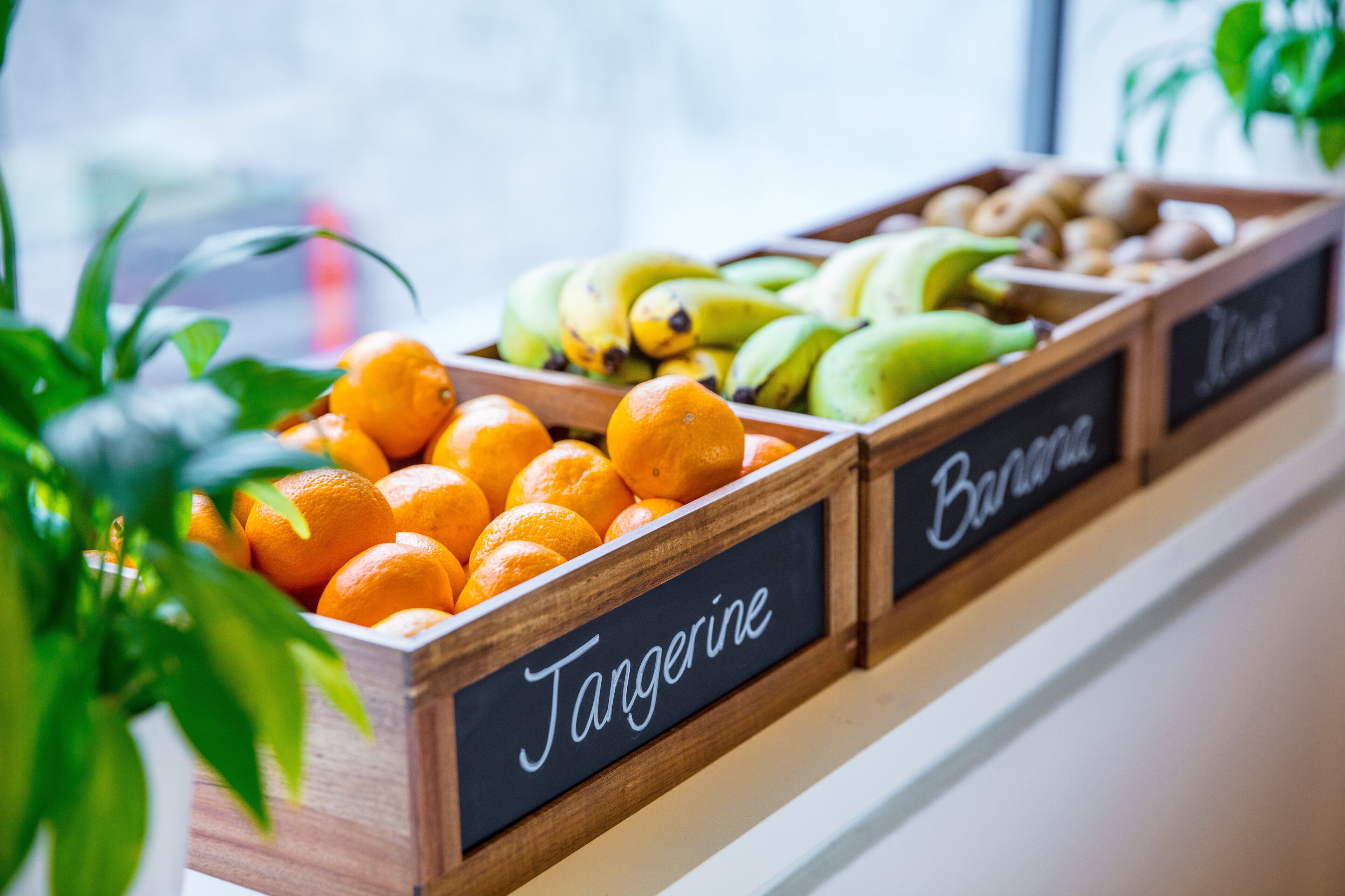 Cestas de madera con frutas como mandarina, plátano y kiwi.