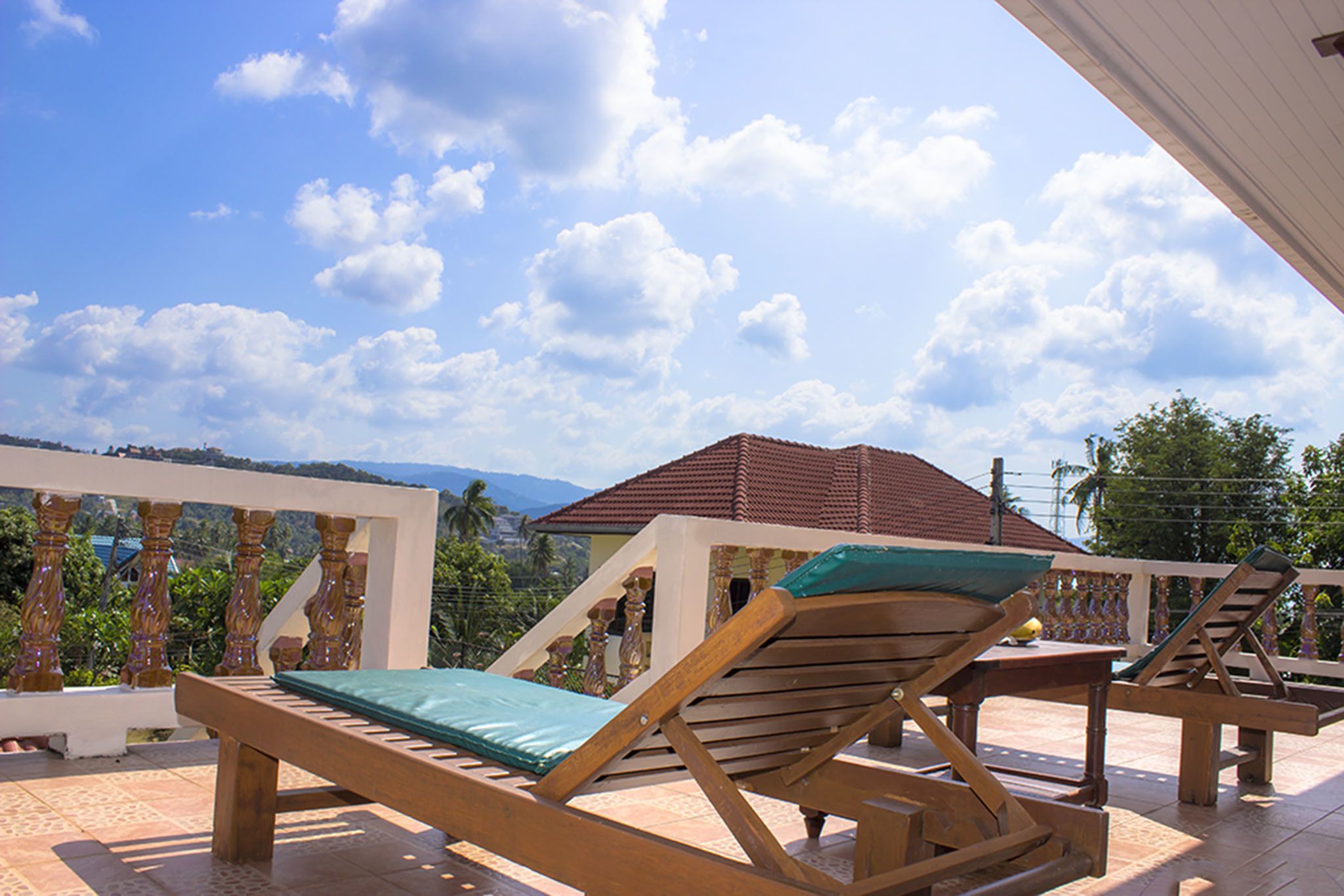 Una terraza con sillones de madera y una mesa, con vista a un paisaje montañoso.