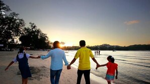 Un grupo de personas caminando por la playa al atardecer.