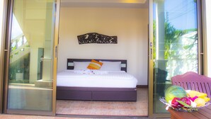 Un dormitorio con cama, un adorno en la pared y una ventana con vistas a la vegetación.