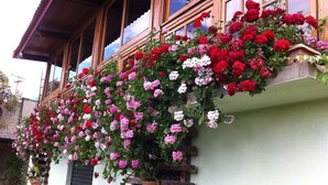 A building with a balcony covered in hanging flower baskets. - Pousada Benevento (Campos do Jordão)