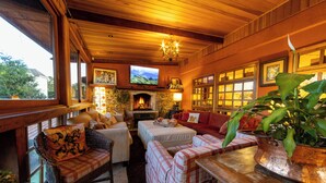 A cozy living room with wicker furniture, a fireplace, and a television. - Pousada Benevento (Campos do Jordão)