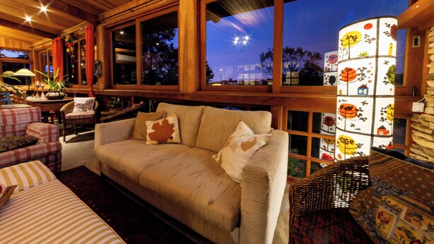 A cozy living room with a sofa, chairs, and a decorative lamp. - Pousada Benevento (Campos do Jordão)