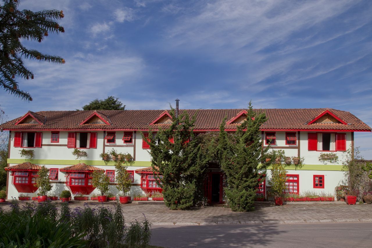 Une rangée de bâtiments traditionnels aux façades rouges et blanches, avec une entrée centrale et des plantes en pot au premier plan.