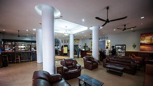 A spacious lobby with leather sofas, a coffee table, and a bar area in the background. - Angkor International Hotel (Phnom Penh)