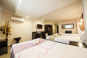 A hotel room with two beds, a desk, a chair, an air conditioner, a TV, and a decorative plant. - Angkor International Hotel (Phnom Penh)