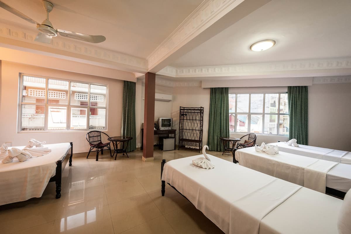 Hotellihuone, jossa on sänky, kaksi yöpöytää, tuoli, työpöytä tietokoneella ja ikkuna, jossa on verhot.