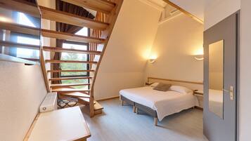 A bedroom with a wooden staircase, a bed, a bedside table, and a wall-mounted light fixture.