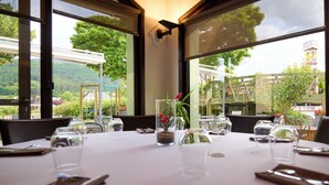A table set for dining with a view of the outdoors, including a bridge and greenery. - Hotel Le Calice du Gevaudan (Banassac)