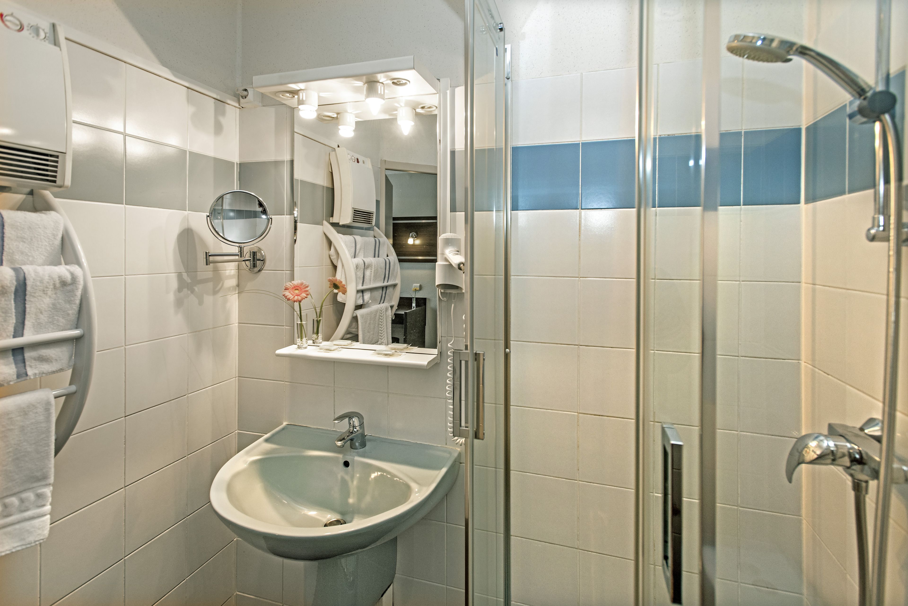 A bathroom with a sink, mirror, towel rack, and shower.
