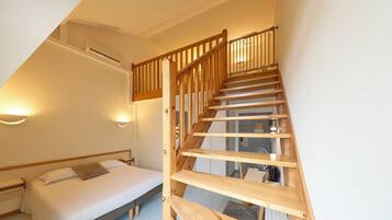 Un dormitorio con escalera de madera, una cama y una mesita de noche.