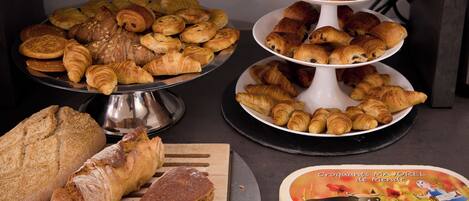Une variété de produits de boulangerie, notamment du pain, des croissants et des pâtisseries, sont présentés sur une table.