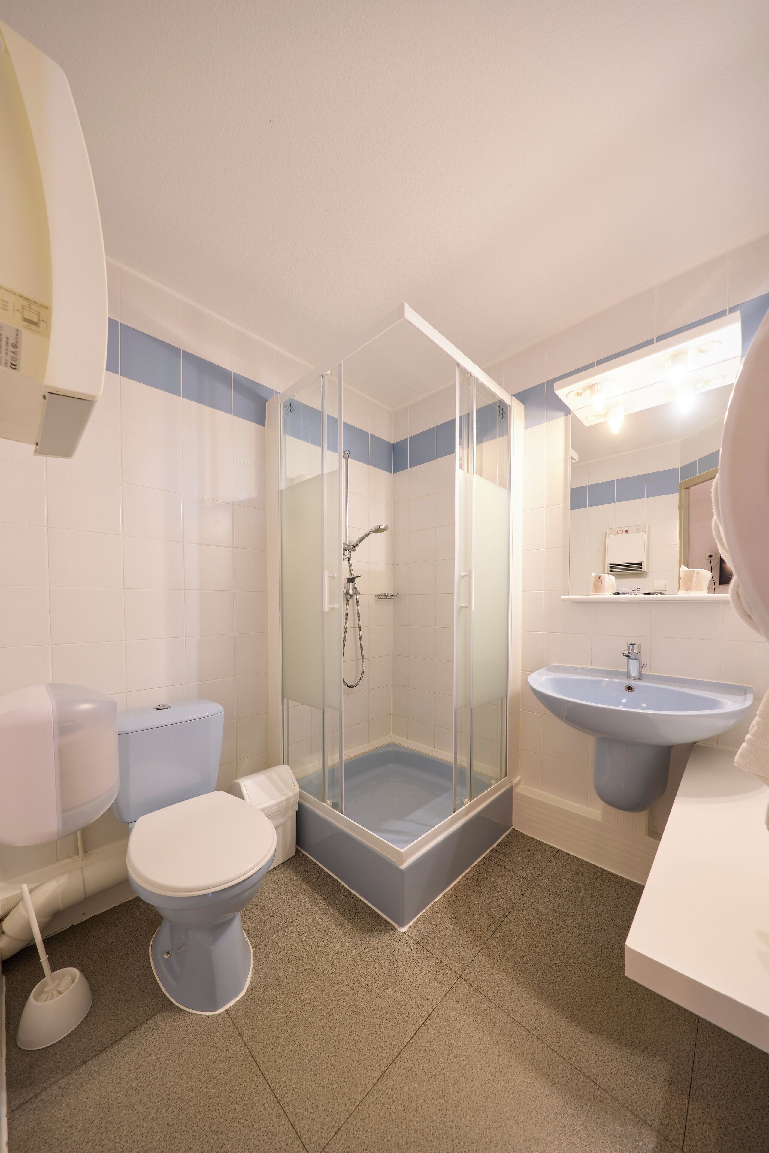 Een badkamer met een glazen douchecabine, een wit toilet, een wastafel en een spiegel.