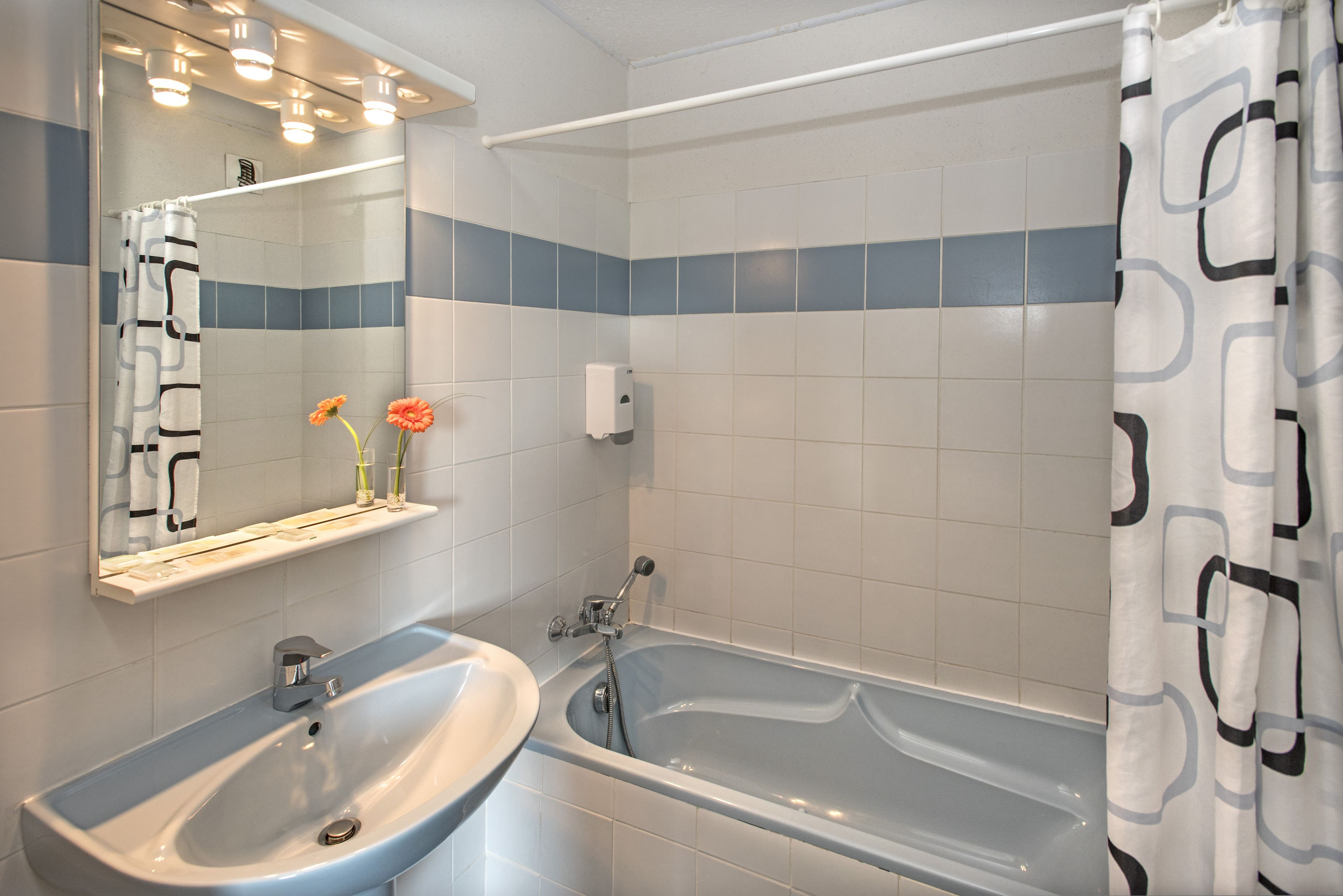 A bathroom with a sink, mirror, and bathtub.
