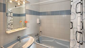 A bathroom with a sink, mirror, and bathtub.