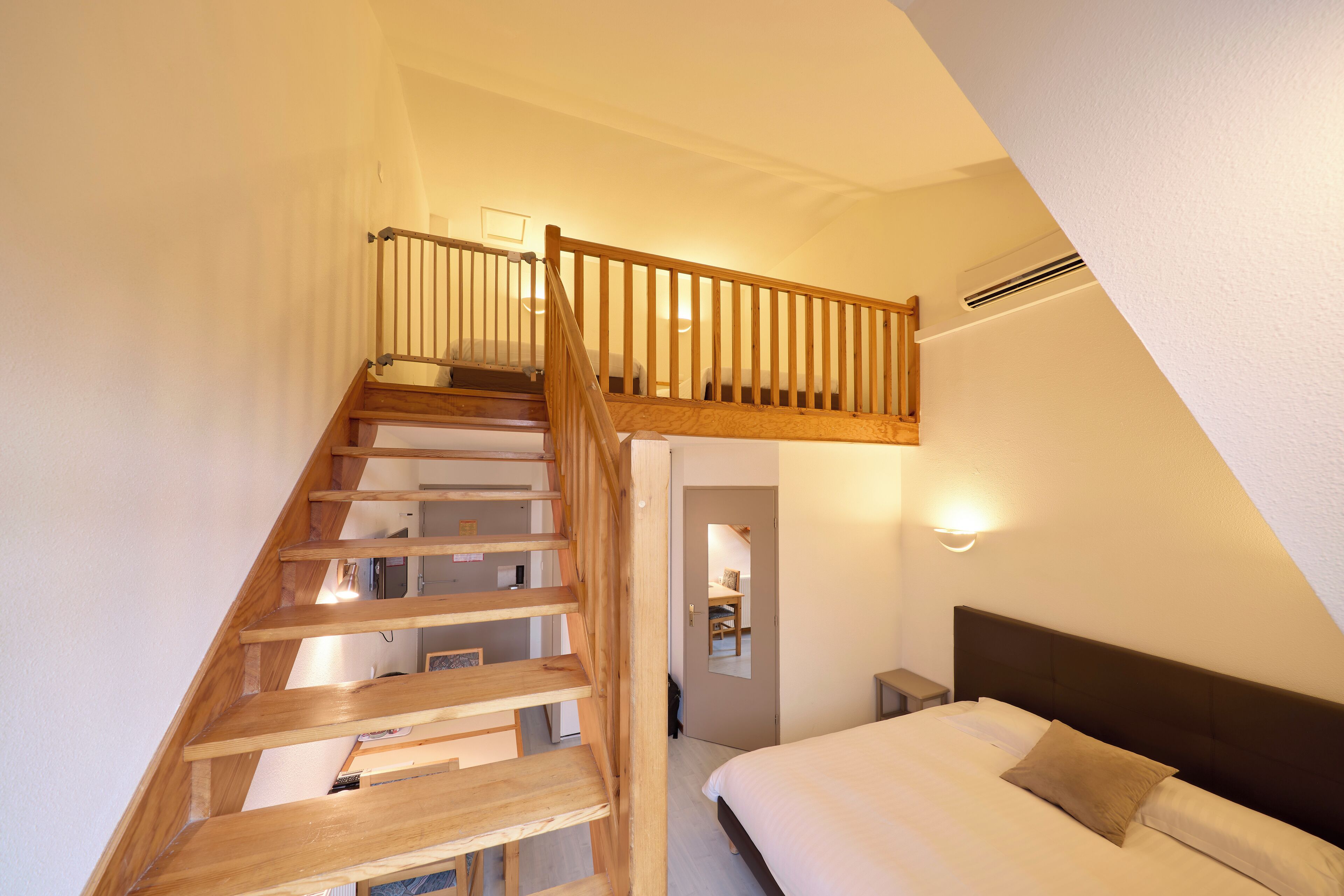 Ein Schlafzimmer mit einer Holztreppe, einem Bett mit weißer Bettwäsche und einem Nachttisch.