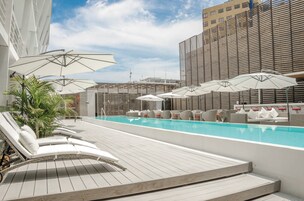 Una piscina al aire libre, sombrillas, sillones reclinables de piscina
