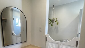 Un couloir avec un banc en bois, un miroir et une porte blanche à panneaux ajourés.