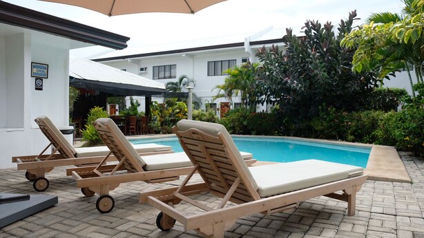 Un espace aménagé au bord de la piscine, avec des chaises longues et une piscine.