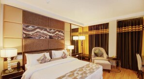 A hotel room with a large bed, two bedside lamps, a chair, a desk, and a large mirror. - Palm Springs Stays (New Delhi)