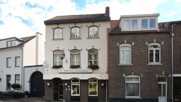 Un hôtel appelé «Hotel Garni De Harsteboom», doté d’une façade classique, de nombreuses fenêtres et d’une entrée imposante.