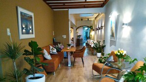 Un grand salon avec un plancher en bois, un canapé, une table à manger et plusieurs plantes en pot.