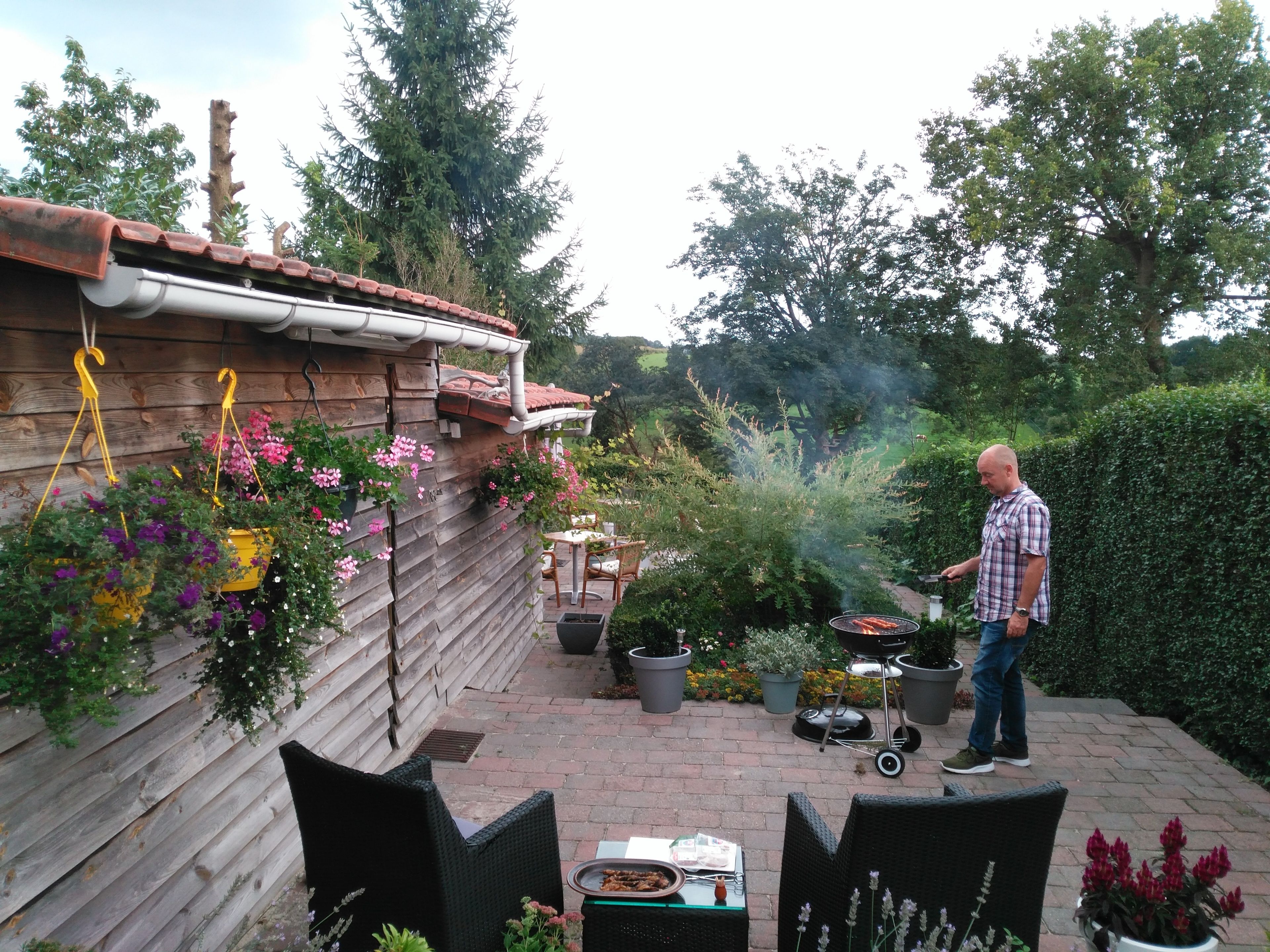 A patio with a grill, potted plants, and outdoor furniture.