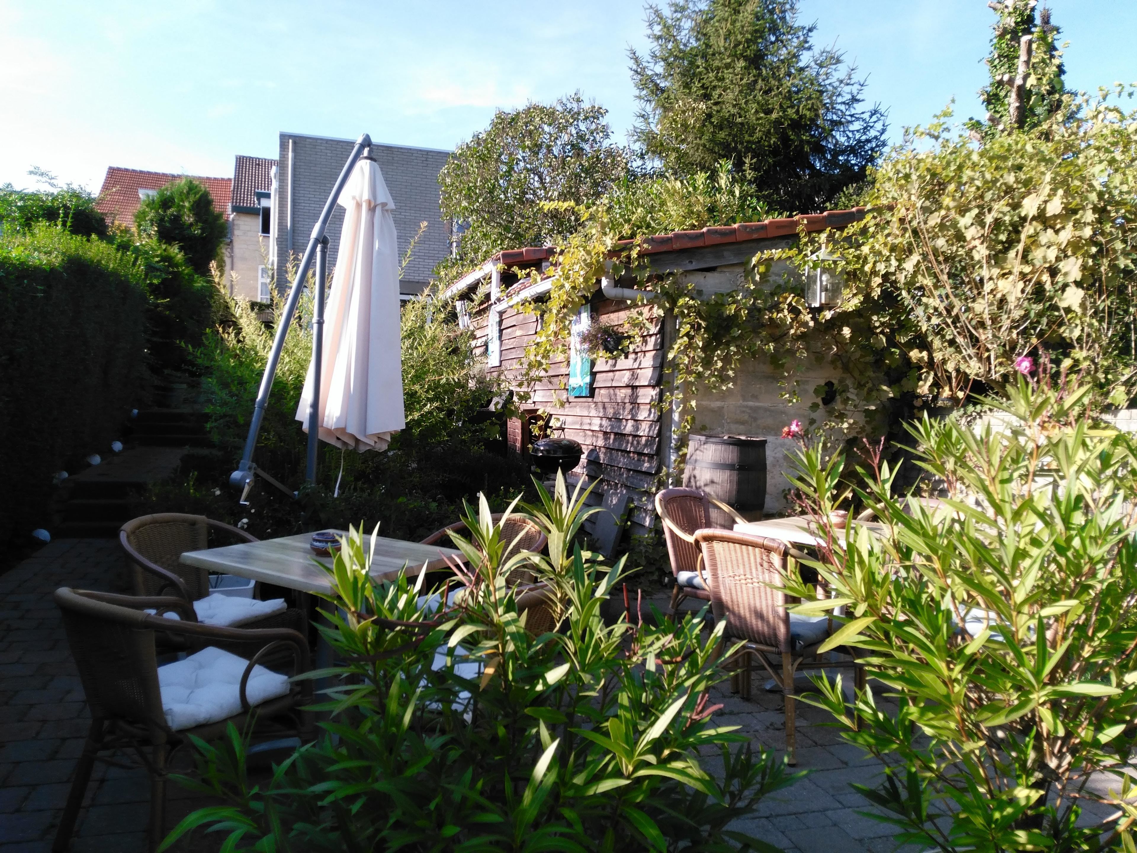 A patio area with wicker furniture, a table, and a white umbrella.