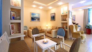 A cozy living room with a sofa set, a coffee table, and a lamp. There are framed pictures on the walls and a plant in the corner. - Bella Vista (Becici)