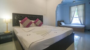 A hotel room with a large bed, a bedside table with a lamp, and a window with curtains. - Azoush Tourist Guesthouse (Fulhadhoo)