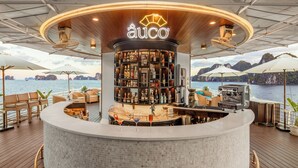 A bar area with a 'auco' sign, bar counter, seating, and a view of the water. - The Au Co Cruise - Longest Cruise 2 Bays (Tuan Chau)