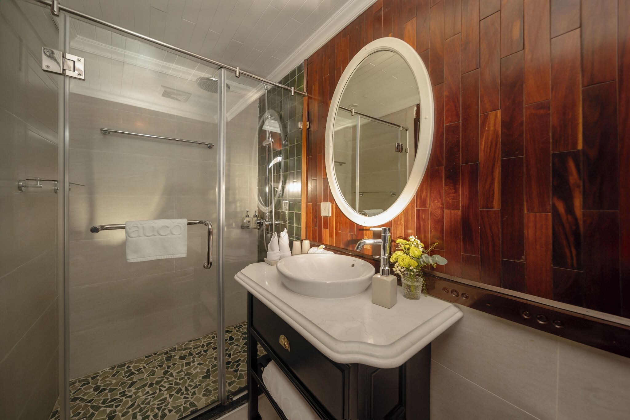 A modern bathroom with a glass-enclosed shower, a white sink, and a large mirror.